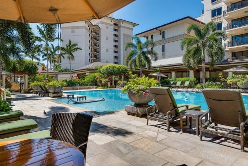 una piscina con sillas y una mesa junto a un edificio en Ko Olina Beach Villas B610, en Kapolei