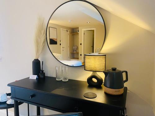a mirror on a table with a tea kettle and a lamp at The Punchbowl Lapworth in Solihull