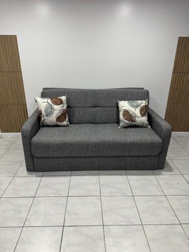 a gray couch with two pillows on a tile floor at Pipo’s perfect place in Jersey City