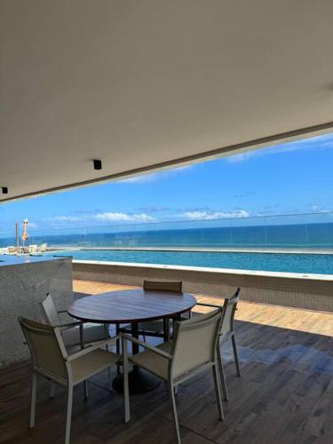 a table and chairs with a view of the ocean at 1/4 sala mobiliado, completo, em Stella Maris/Salvador in Salvador