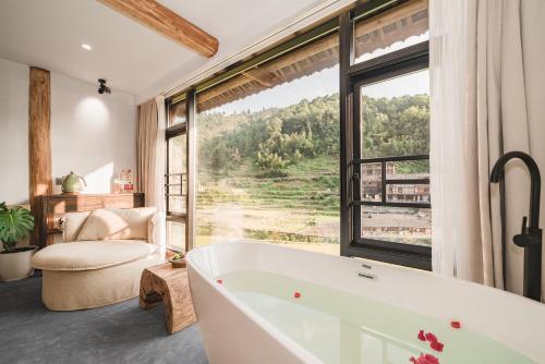 uma casa de banho com banheira e uma grande janela em 肇兴溪舍山堂 Creekside Inn em Liping