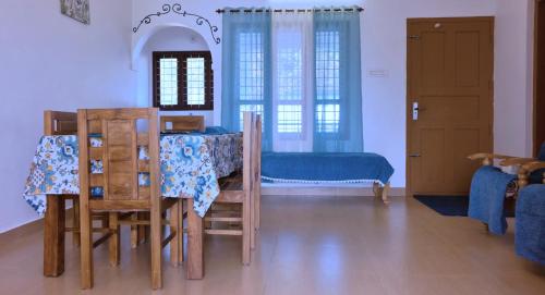 a dining room with a table and chairs and a bedroom at Moon Wings Mountain Resort, Kanthalloor in Kanthalloor