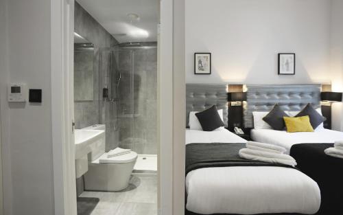 een slaapkamer met 2 bedden en een badkamer met een douche bij The 29 London in Londen