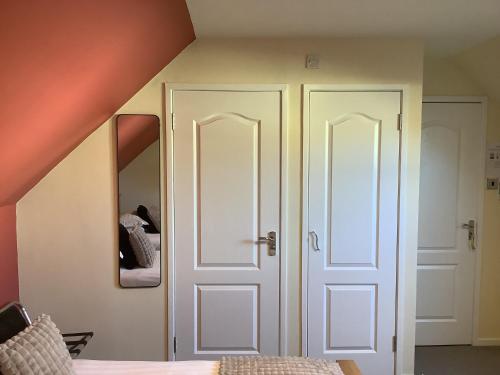 a bedroom with two white doors and a bed at Heatherbrae Guest House in Kyle of Lochalsh