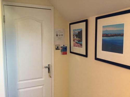 a white door with three pictures on the wall at Heatherbrae Guest House in Kyle of Lochalsh