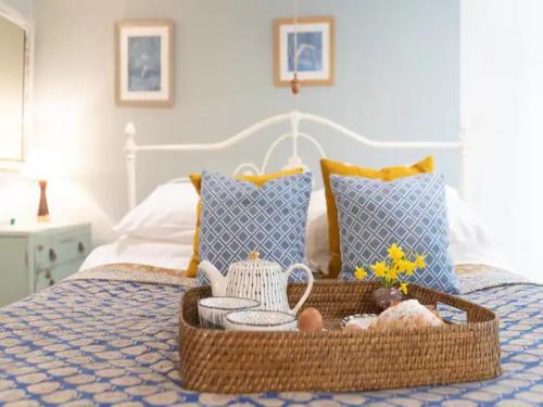a basket of food and dishes on a bed at Pass The Keys Wilf's Barn, Wedmore a romantic cottage for two in Wedmore