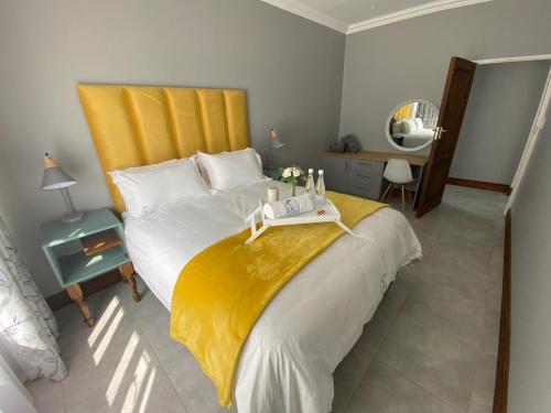 - une chambre avec un grand lit et une tête de lit jaune dans l'établissement StaySure Guesthouse, à Alberton