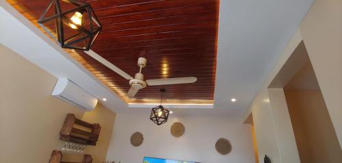 a ceiling fan in a living room with a wooden ceiling at Homes By Sandra in Kilifi