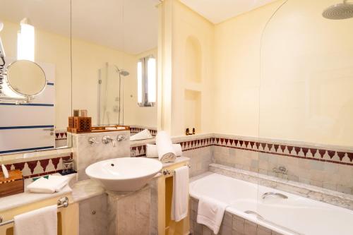 a bathroom with a tub and a sink and a bath tub at Le Médina Essaouira Thalassa Sea & Spa - MGallery Collection in Essaouira