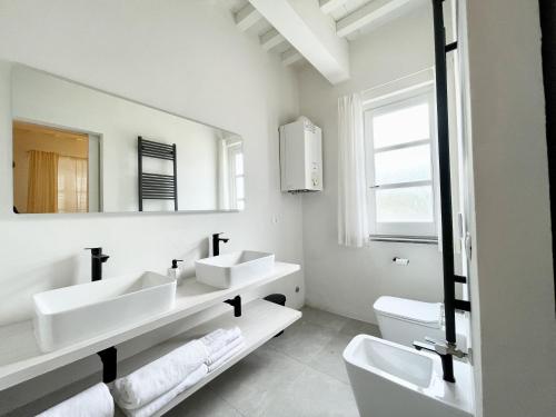 a white bathroom with two sinks and a mirror at Agriturismo Antica Corte - Lilla' in Montepulciano