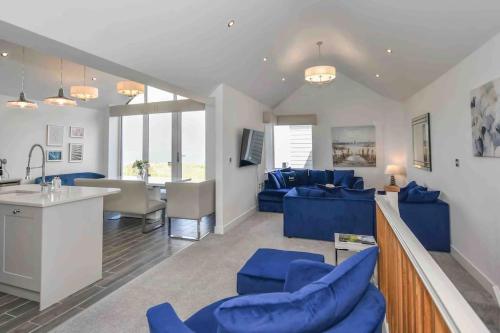 a living room with blue couches and a kitchen at Harbour Sands - 4 Bed With Stunning Coastal Views in Amble