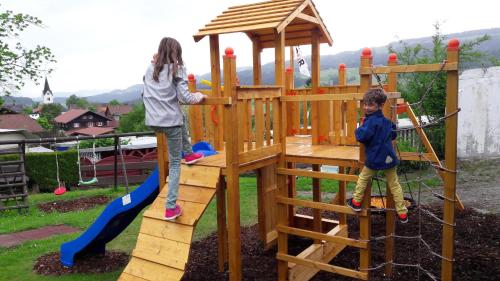 dwójka małych dzieci bawiących się na drewnianym placu zabaw w obiekcie Wolpertinger | Camping-Aach w mieście Oberstaufen