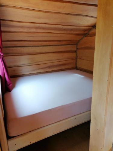 a bed in a cabin with a wooden wall at Wolpertinger | Camping-Aach in Oberstaufen