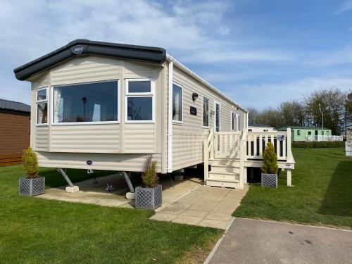 a white tiny house parked in a yard at Tattershall Lakes Kingfisher Caravan 8 berth with Hot tub & WiFi in Tattershall
