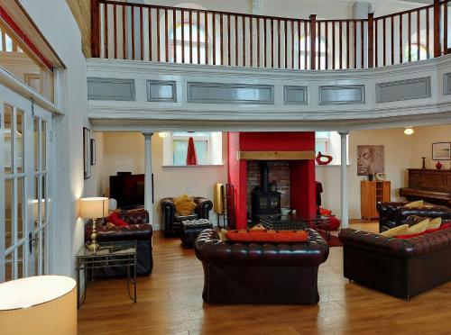 a living room with leather couches and a fireplace at Ty Capel in Tywyn in Tywyn