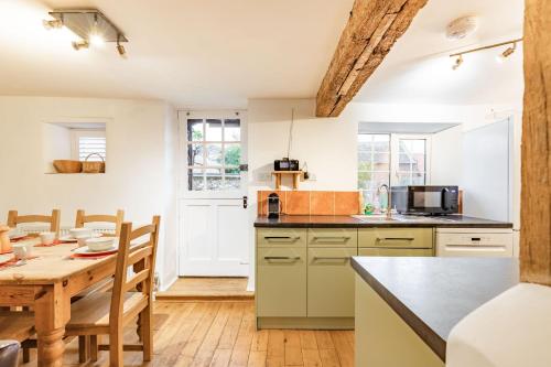 a kitchen with a table and a dining room at 1 Ruscon Cottage in Brancaster