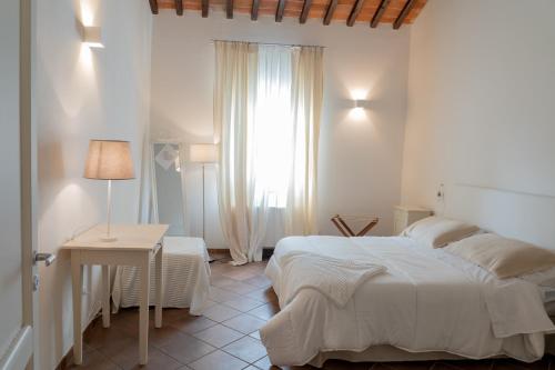 a bedroom with a bed and a table and a window at Agriturismo Antica Corte - Ortensie in Montepulciano