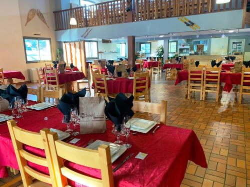 レ・ザングルにあるChalet Ma Neou Centre De Vacancesの赤いテーブルクロスのテーブルと椅子が備わるレストラン