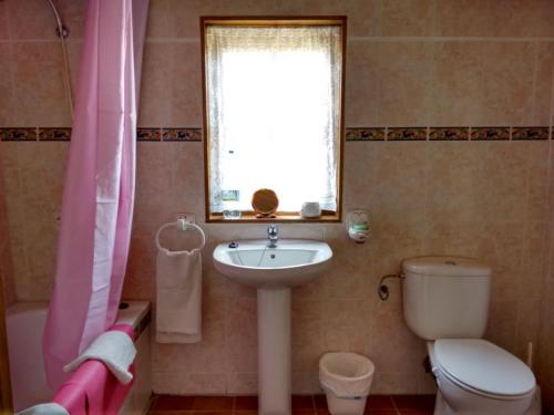 a bathroom with a sink and a toilet and a window at Finca La Piedra Holidays in Alora