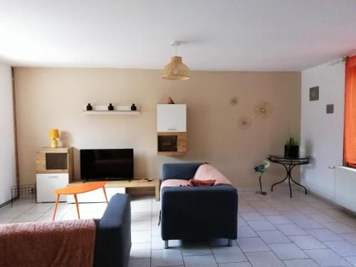 un salon avec un canapé et une télévision dans l'établissement Le Marais, à Merville