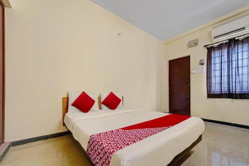 a bedroom with a bed with red pillows on it at Hotel Trident Inn in Coimbatore