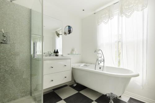a bathroom with a tub and a shower and a sink at The Kensington Place - Stylish 1BDR Flat in London
