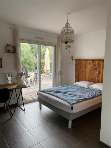 een slaapkamer met een bed en een glazen schuifdeur bij Villa proche bassin 10 personnes in Mios