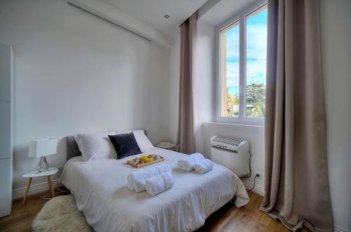 une chambre blanche avec un lit avec des serviettes dessus dans l'établissement Spacieux et confortable 3 pieces A2B248, à Cannes