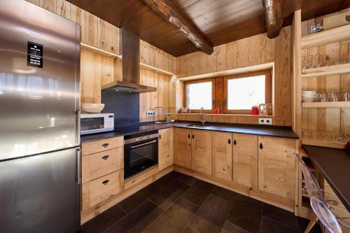 a kitchen with wooden cabinets and a stainless steel refrigerator at Borda Climent,Lujo Rustico en Grandvalira in Canillo