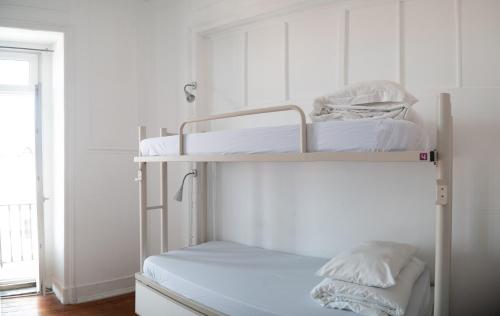 two bunk beds in a room with white walls at Safestay Lisbon Bairro Alto in Lisbon