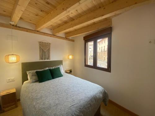 Un dormitorio con una cama con almohadas verdes y una ventana en El mirador de Mati en Torrecilla en Cameros