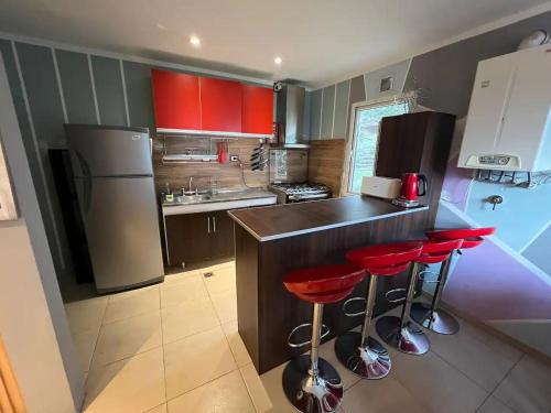 a kitchen with red stools at a counter with a refrigerator at Casa de Ushuaia in Ushuaia