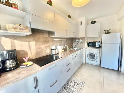 uma cozinha com armários brancos e uma máquina de lavar e secar roupa em Arènes by Welcome to Cannes em Cannes