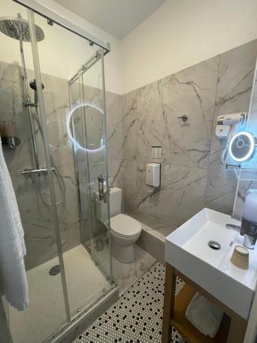y baño con ducha, aseo y lavamanos. en Balzac Hôtel, en Fougères