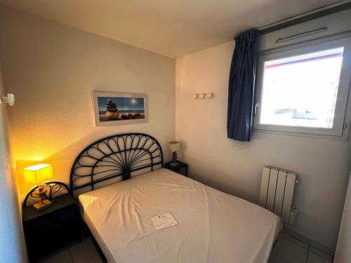 une chambre avec un lit blanc et une fenêtre dans l'établissement LES TERRASSES DE SAVANNA Joli 2 pièces cabine piscine Rochelongue Cap d'Agde, au Cap d'Agde