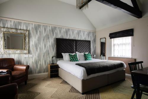 a bedroom with a bed and a chair and a mirror at The Huntsman of Brockenhurst in Brockenhurst