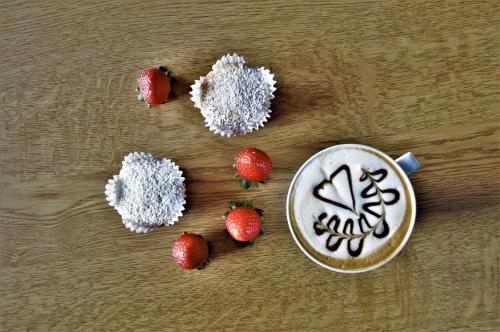a cup of cappuccino and strawberries on a table at Pension Panorama in San Lorenzo di Sebato