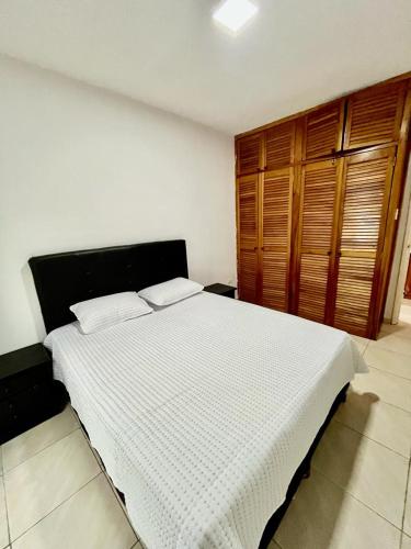 a bedroom with a large white bed with wooden cabinets at Casas Bote in El Morro de Barcelona