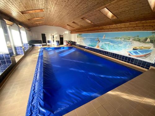 a large blue swimming pool with a large painting on the wall at Vast, Elegant Home with Indoor Pool & Sauna near Popular Golf Course in Kington