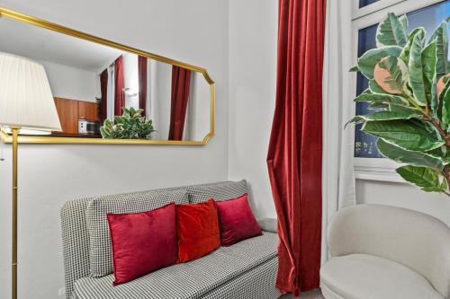 Habitación con sofá, almohadas rojas y silla. en Central - 30 m² - Next to Augarten, en Viena