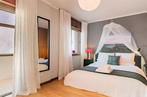 a bedroom with a white bed with a canopy at Stunning View Apartament by BnbHost in Vila Nova de Gaia