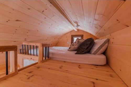 uma cama num pequeno quarto num chalé de madeira em Chalet Éloise à louer avec spa Mauricie em Saint-Alexis-des-Monts