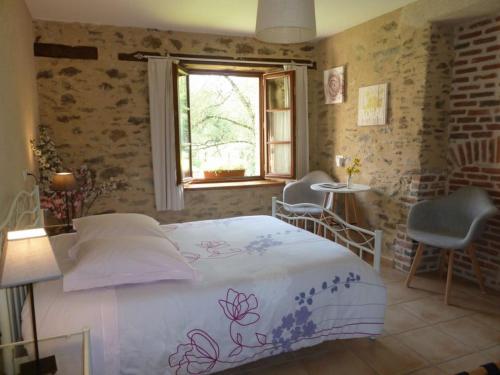 a bedroom with a bed and a window and a table at Le Moulin de Drapras in Chemillé