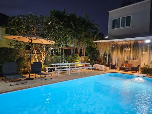 a swimming pool at night with a table and umbrella at My Home Pool Villa Hatyai in Hat Yai