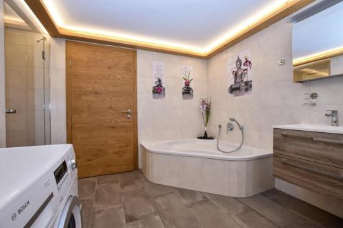 a bathroom with a tub and a sink and a washing machine at Landhaus Kirchberg in Kirchberg in Tirol