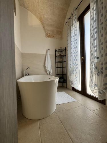 a white bath tub in a bathroom with a window at Le Pietre Apartments in Ostuni