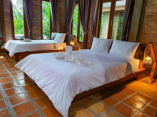a bedroom with two beds with white sheets at Kung Nok Tha Resort Nakhon Si Thammarat in Nakhon Si Thammarat