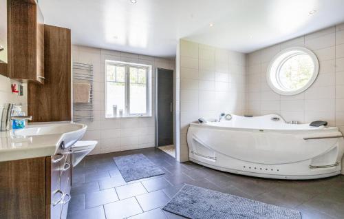 baño blanco grande con bañera y lavamanos en Nice Home In Vaggeryd With Kitchen, en Vaggeryd