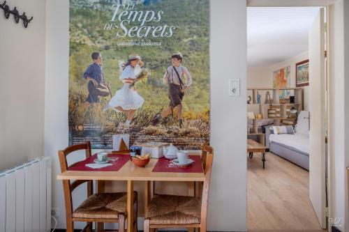 een woonkamer met een tafel en een filmposter bij La Halte Provençale vaste gîte T1 avec jardin entre mer et collines in Roquevaire
