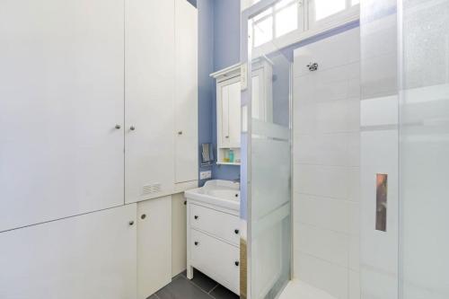 La salle de bains est pourvue de placards blancs et d'un lavabo. dans l'établissement Luxurious Apartment in Le Marais, à Paris